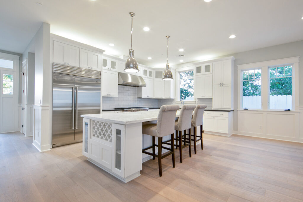 Modern kitchen interior featuring Dove City BWS bright white shaker cabinets, a large center island, and contemporary lighting.