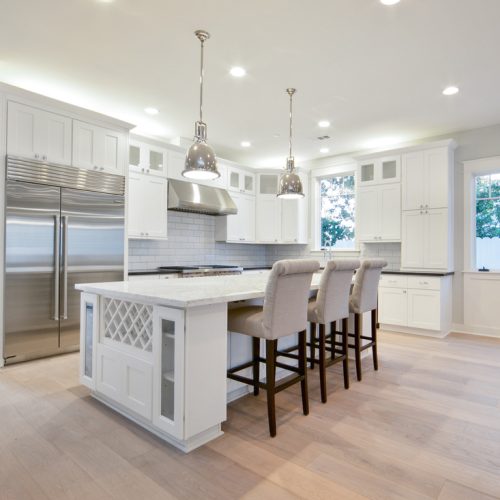 Modern kitchen interior featuring Dove City BWS bright white shaker cabinets, a large center island, and contemporary lighting.